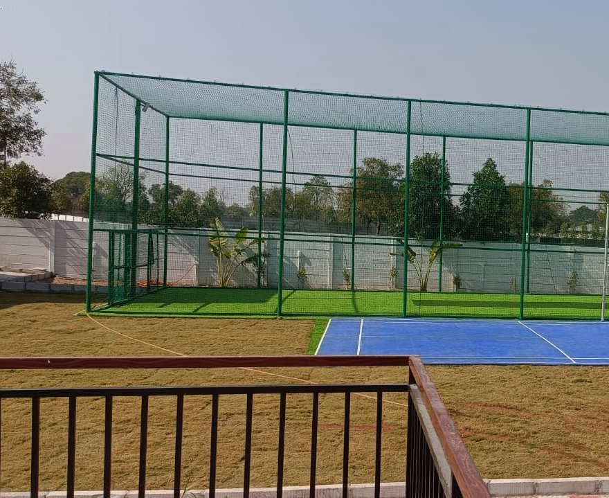 The netted box cricket cage over turf.