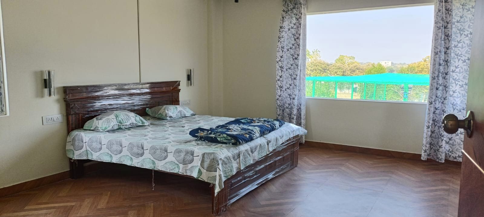 A bedroom with a carved wooden bed and a large window looking onto the grounds.