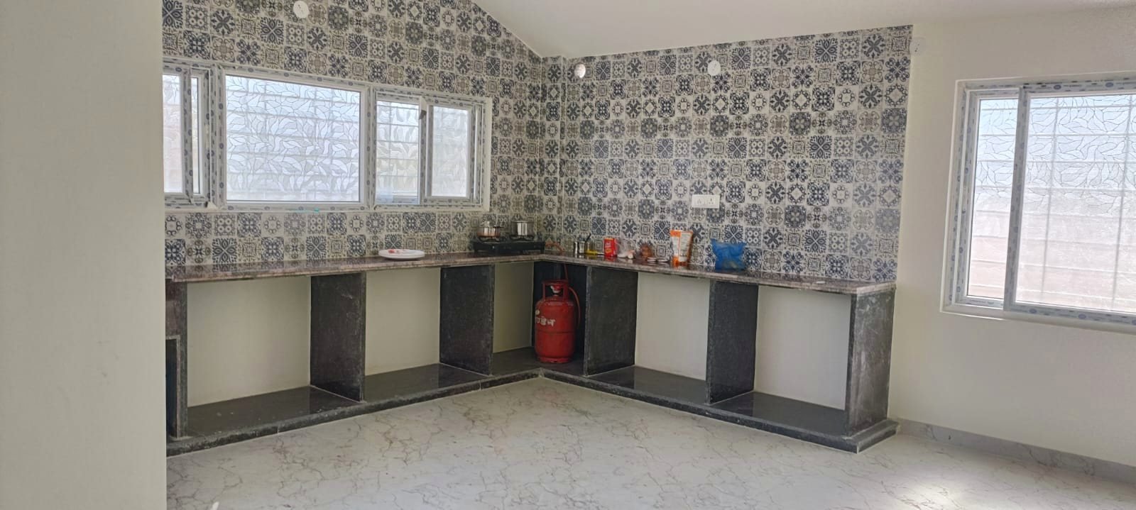 The kitchen with patterned tiled walls and a long preparation counter.