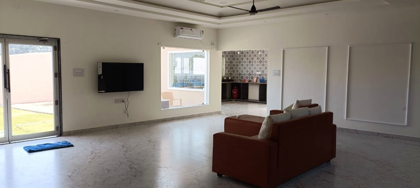 The lounge with a wall-mounted television, sofa and the open kitchen beyond.