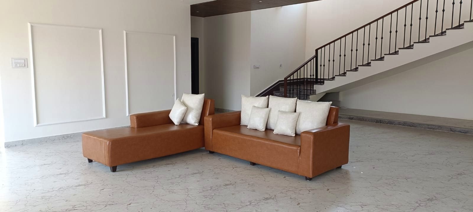 The living room with its tan sectional sofa beside the staircase.