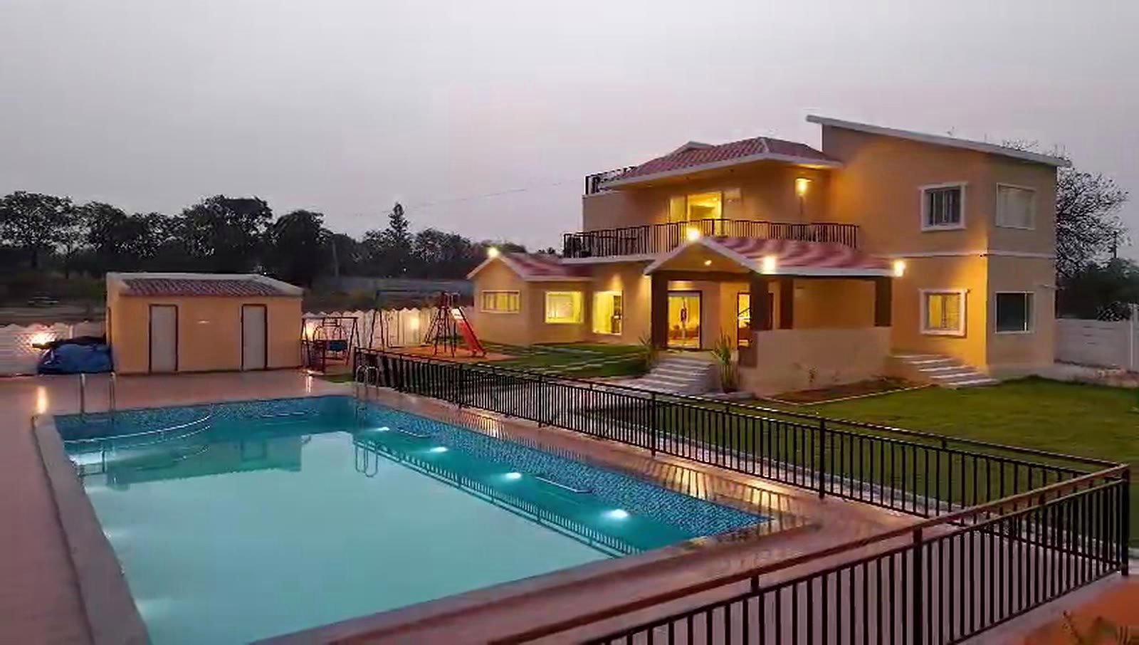 The farmhouse and pool at twilight, seen from the far side of the water.