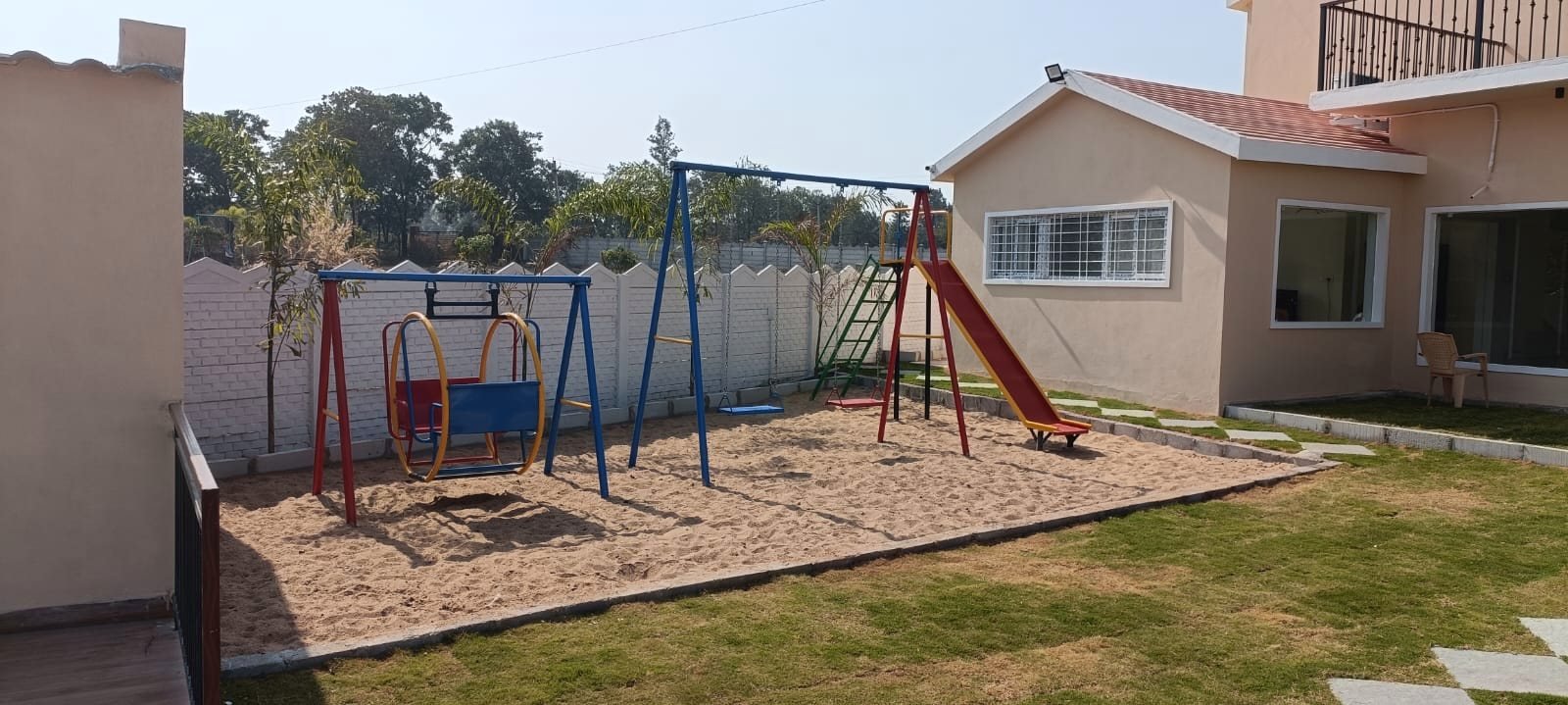 The children’s play area with swings, a slide and a sand pit beside the house.