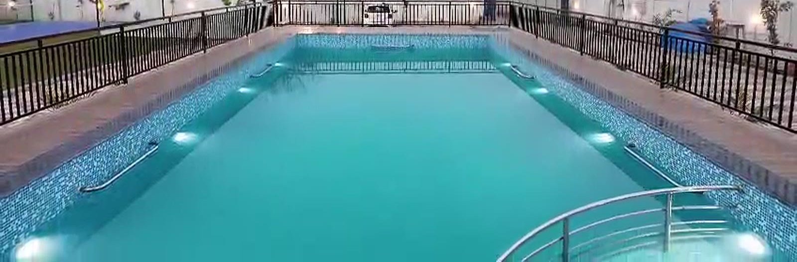 The swimming pool at dusk with its underwater lights on.